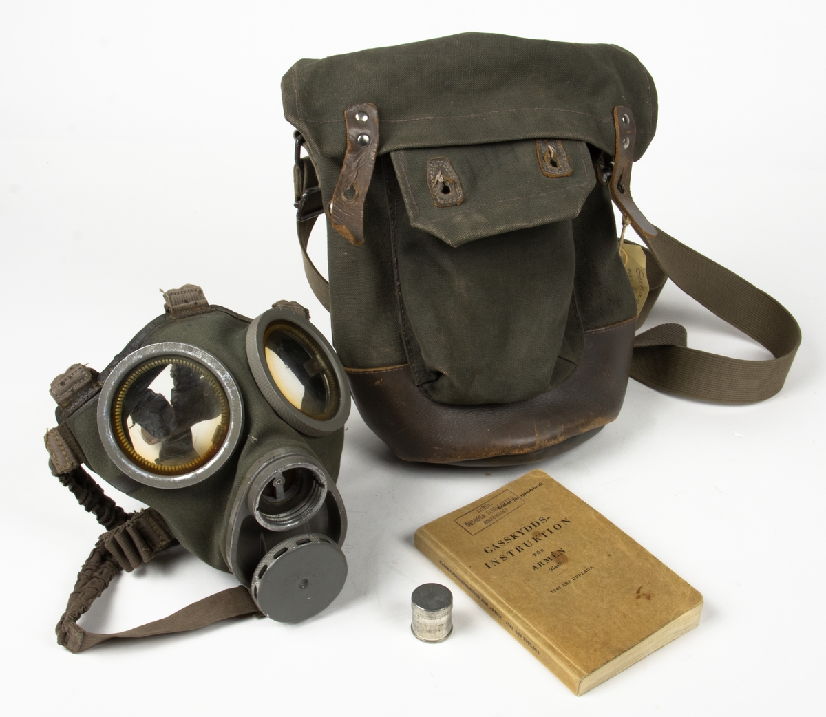 1. Gasmask med tygväska. Innehåller även instruktionsbok..
2. Gasmask av gummi med filter Typ 21.
3. Filter till gasmask, koloxidfilter M2311-721.