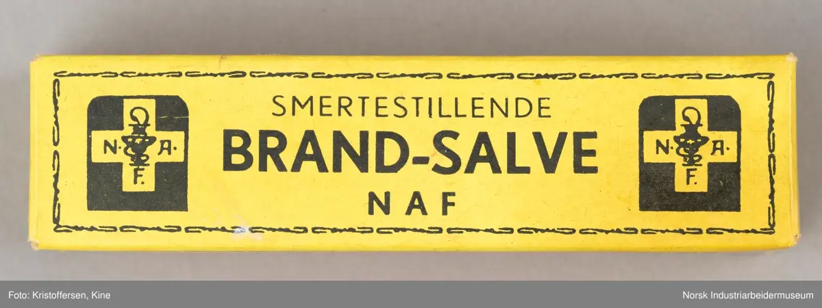 Tube med smertestillende brannsalve i original emballasje. Esken er avlang og gul med sort skrift-