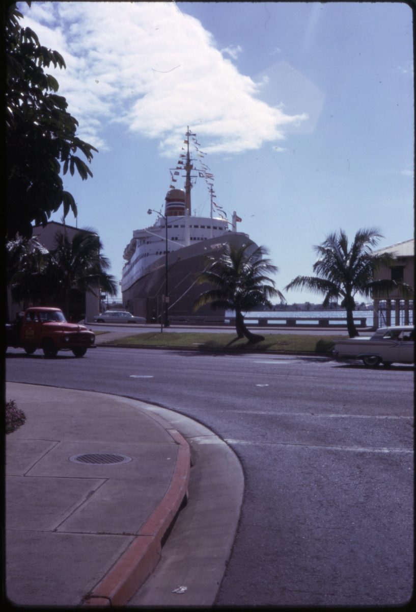 Cruiseskipet 'M/S Sagafjord' fortøyd bak biler og palmer, trolig på Hawaii. 'Sagafjord' Around The World via Africa Cruise 1966.