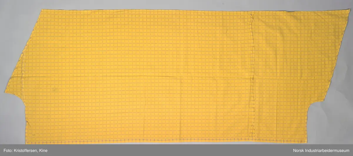 Gult stoffstykke satt sammen av tre stykker. Det er skjøtet 37 cm. fra høyre kant oppe. Pen skjøt, følger mønsteret. Jarekantene er ikke klippet av, men ligger på baksiden som sømningsmonn. På den andre siden, venstre side, er det satt på et lite stoffstykke ekstra. Det er gjort på samme måte, altså med en pen skjøt der mønsteret stemmer. Det er smale falder rundt hele stykket, men i overkant er den litt bredere. Det er et hull i stoffet. Stoffet er generelt ikke veldig slitt, og det virker ikke som dette hullet er forårsaket av alminnelig slitasje. Det må snarere være resultat av en spesiell påvirkning på akkurat det stedet. Pålimt lapp: F 09.