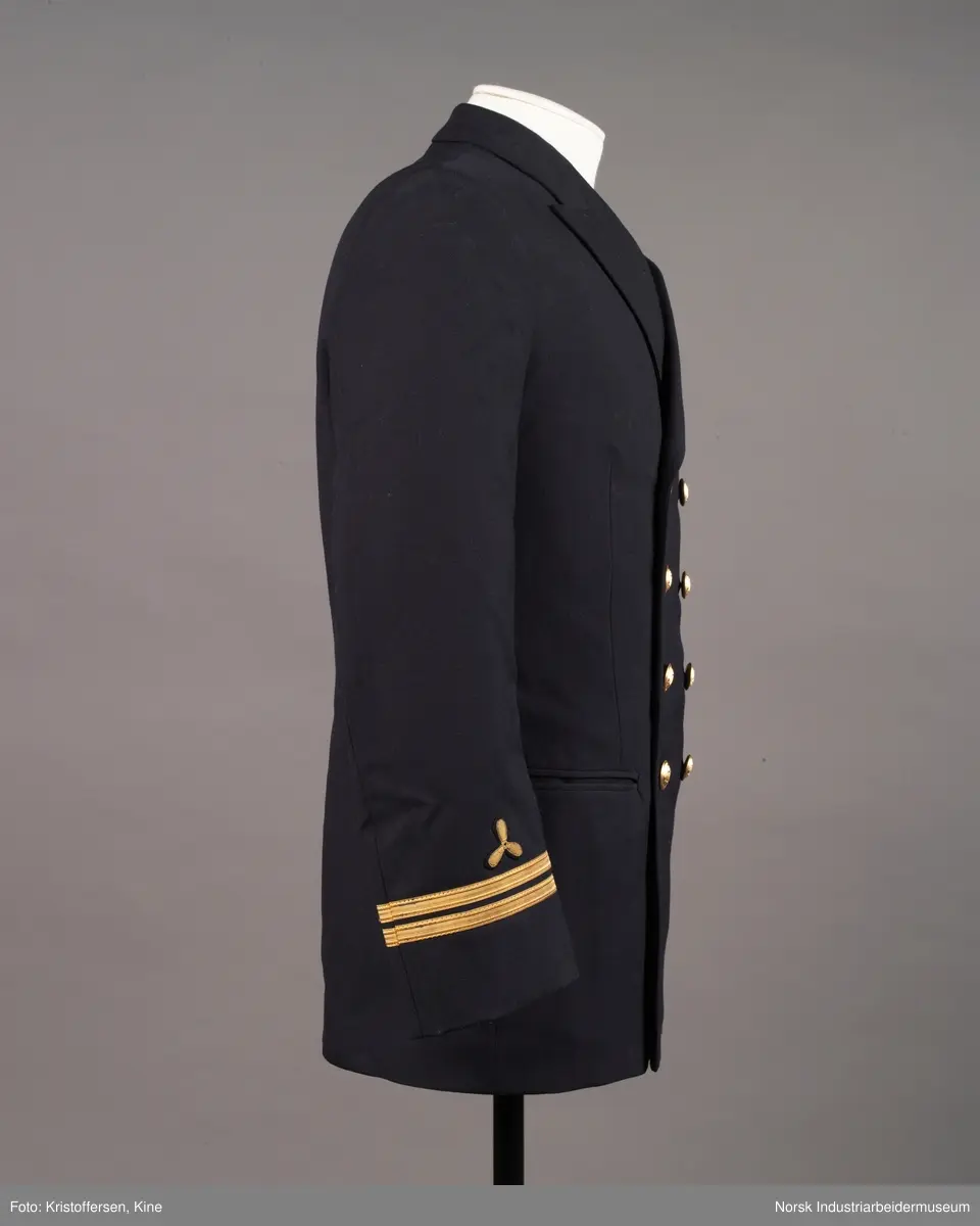 Uniformsjakke til maskinist med åtte gullknapper med ankerlogo. To striper og propellogo i gull på hvert erme.