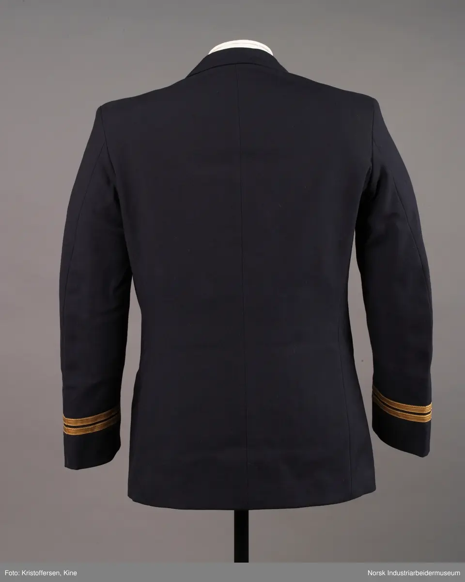 Uniformsjakke til maskinist med åtte gullknapper med ankerlogo. To striper og propellogo i gull på hvert erme.