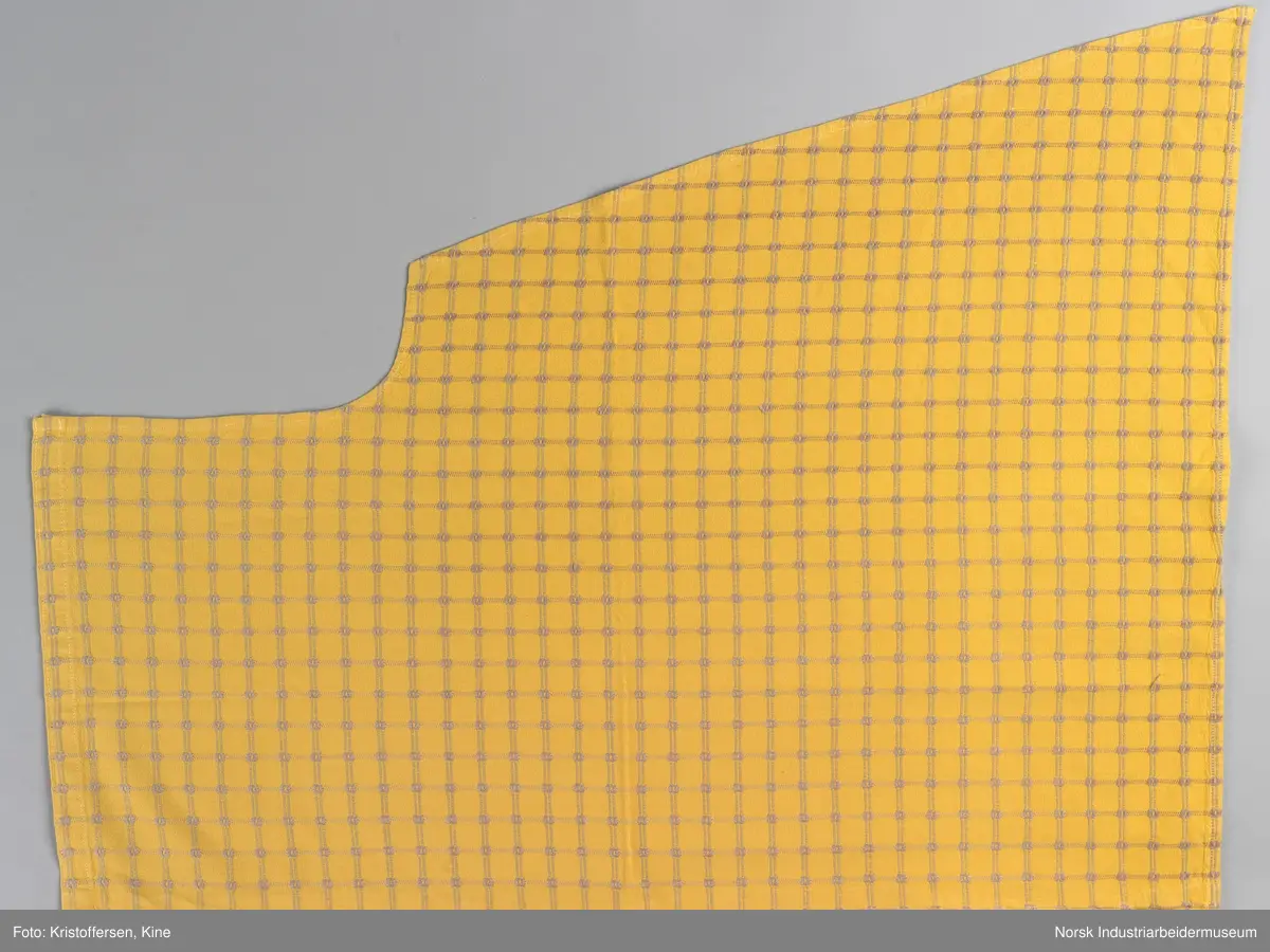 Gult stoffstykke satt sammen av tre stykker. Det er skjøtet 37 cm. fra høyre kant oppe. Pen skjøt, følger mønsteret. Jarekantene er ikke klippet av, men ligger på baksiden som sømningsmonn. På den andre siden, venstre side, er det satt på et lite stoffstykke ekstra. Det er gjort på samme måte, altså med en pen skjøt der mønsteret stemmer. Det er smale falder rundt hele stykket, men i overkant er den litt bredere. Det er et hull i stoffet. Stoffet er generelt ikke veldig slitt, og det virker ikke som dette hullet er forårsaket av alminnelig slitasje. Det må snarere være resultat av en spesiell påvirkning på akkurat det stedet. Pålimt lapp: F 09.