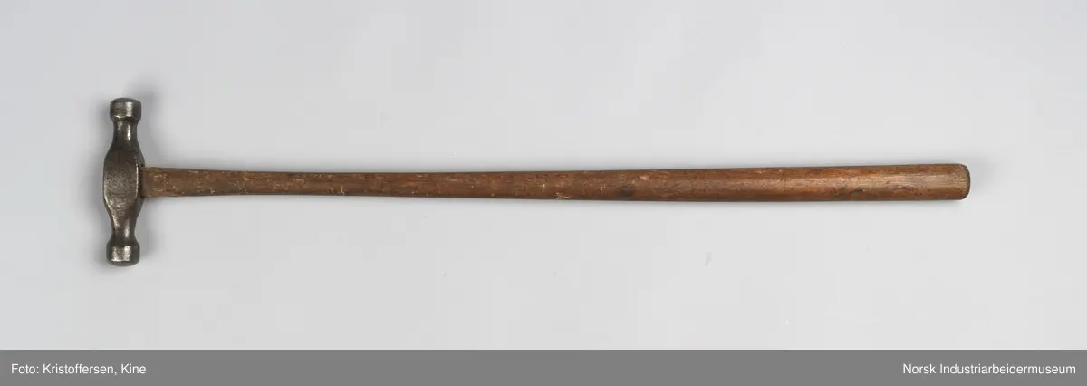Vognvisitørhammer. Skaftet er gjennomgående. Hodet er blankslitt, metallisk av farge. Hodet har nok vært litt slarkete, for det er satt i en skrue i treverket i toppen for å utvide det slik at hammerhodet sitter godt på. Ingen stempler eller merker.