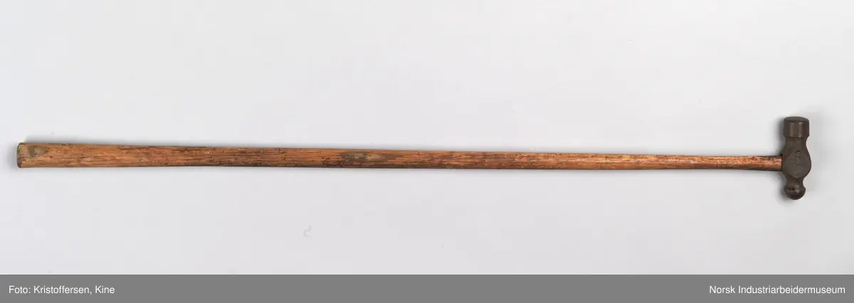 Vognvisitørhammer. Skaftet er 79 cm. langt. Skaftet er gjennomgående. Hodet er veldig svart og sitter litt slarkete. Merking: Lok. 9 er svidd inn. På hammerhodet står det: ½ lbs. Germany. Det er også et stempel i form av en stigbøyle