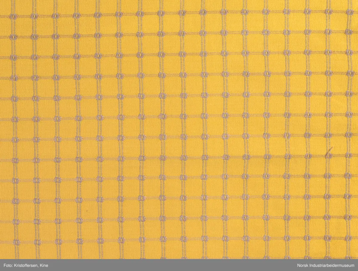 Gult stoffstykke satt sammen av tre stykker. Det er skjøtet 37 cm. fra høyre kant oppe. Pen skjøt, følger mønsteret. Jarekantene er ikke klippet av, men ligger på baksiden som sømningsmonn. På den andre siden, venstre side, er det satt på et lite stoffstykke ekstra. Det er gjort på samme måte, altså med en pen skjøt der mønsteret stemmer. Det er smale falder rundt hele stykket, men i overkant er den litt bredere. Det er et hull i stoffet. Stoffet er generelt ikke veldig slitt, og det virker ikke som dette hullet er forårsaket av alminnelig slitasje. Det må snarere være resultat av en spesiell påvirkning på akkurat det stedet. Pålimt lapp: F 09.