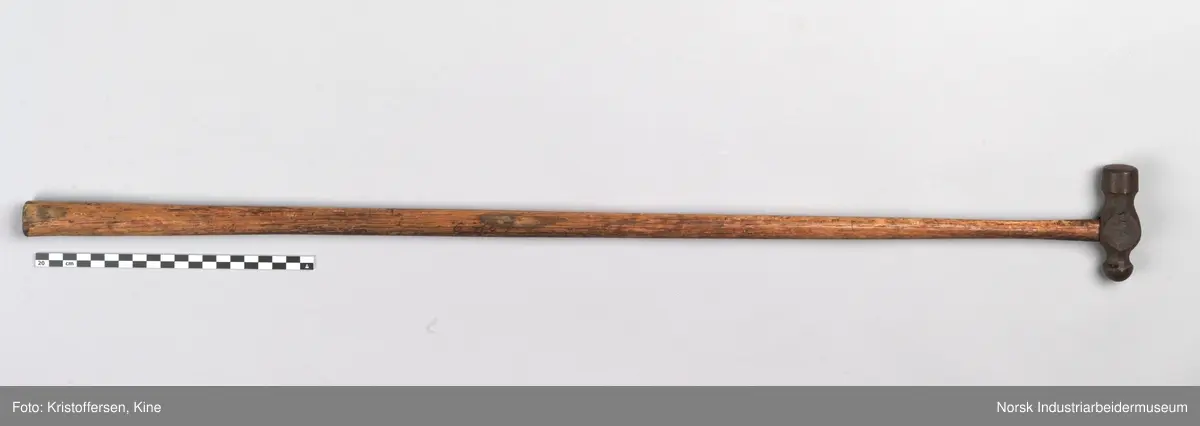 Vognvisitørhammer. Skaftet er 79 cm. langt. Skaftet er gjennomgående. Hodet er veldig svart og sitter litt slarkete. Merking: Lok. 9 er svidd inn. På hammerhodet står det: ½ lbs. Germany. Det er også et stempel i form av en stigbøyle