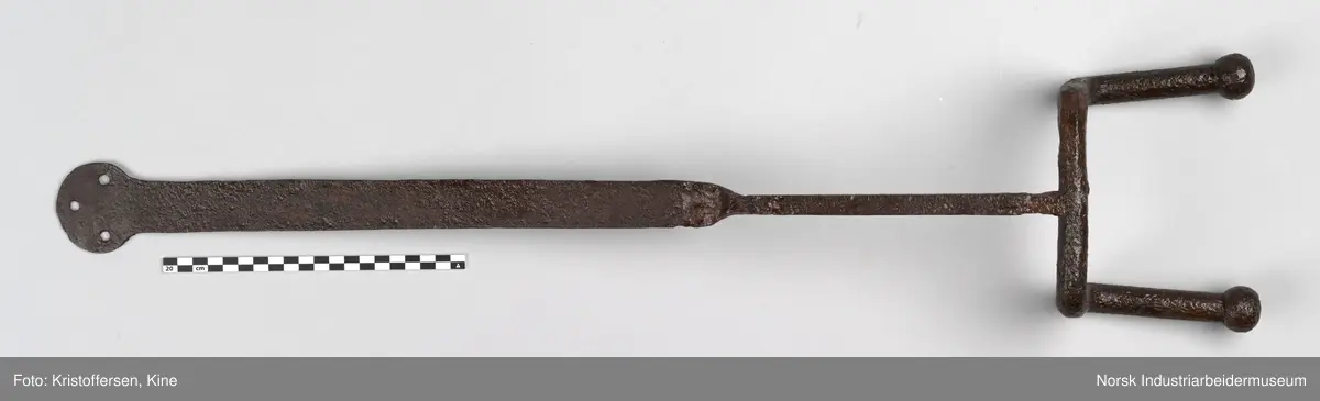 Denne gjenstanden er funnet i ett eller annet av jernbanens bygg. Gjenstanden framkommer som hel og fin og i god stand. Den har ingen slitasjemerker. Det er umulig å si om det har vært spiker eller skruer gjennom hullene og om den dermed har vært hengt opp eller festet på noen måte. Lengden på hele gjenstanden er 81 cm. Det er en skjøt på skaftet, som tyder på at to deler er sveiset sammen. Gjenstanden er forsiktig konservert foran utstillingen på Rjukan stasjon, det vil si at den er pusset med fint sandpapir og har fått et tynt lag voks. 
Ingen vet hvor den kommer fra, hvor den hører til eller hva den har vært brukt til.