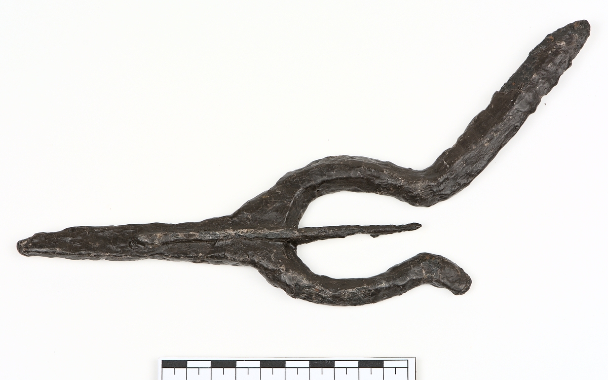 Ljuster av järn med spets inom starka, lyraformade sidostycken, som mitt för spetsen böjer av snett utåt sidorna.