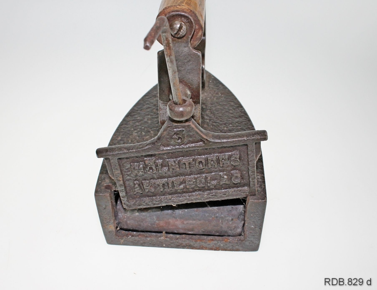 Strykejern i støpt jern. Jernet er innhult med rom for en stein/bolt som kan tas ut og varmes på ovnen. I bakkant på strykejernet er det en luke som går i et spor og som kan løftes opp, slik at steinen kan tas ut/settes inn. Et handtak i tre er festet med skruer til to jern-"stenger" som er festet med skruer til selve jernet. Innstøpt på luka: Mølntorps aktiebolag.