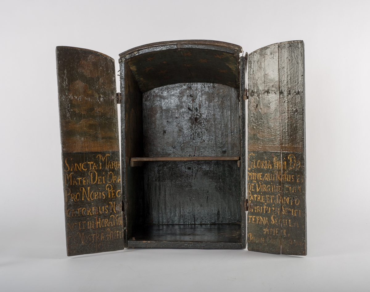 Sortmalt skap med dekor i gull. Bønnetekster på latin, samt Cicignon sitt våpenskjold, og årstallet 1657.



Venstre dør: Utdrag fra følgende bønn:
Ave Maria, gratia plena
Dominus tecum, benedicta tu
In mulieribus et benedictus
Fructus ventris tui Iesus.
Sancta Maria, Mater Dei,
Ora pro nobis peccatoribus,
Nunc et in hora mortis nostrae.
Amen


Norsk:
Hill deg, Maria, full av nåde,
Herren er med deg,
velsignet er du iblant kvinnene,
og velsignet er ditt livs frukt, Jesus.
Hellige Maria, Guds mor,
be for oss syndere,
nå og i vår dødstime.
Amen.

Bak:
Salve, Regina, Mater misericordiæ,
vita, dulcedo, et spe nostra, salve.
Ad te clamamus exsules filii Hevæ,
Ad te suspiramus, gementes et flentes
in hac lacrimarum valle.
Eia, ergo, advocata nostra, illos tuos
misericordes oculos ad nos converte;
Et Jesum, benedictum fructum ventris tui,
nobis post hoc exsilium ostende.
O clemens, O pia, O dulcis Virgo Maria.

Norsk:
Hill deg, Dronning, barmhjertighetens Mor.
Du vårt liv, vår fryd og vårt håp, vær hilset!
Til deg roper vi, Evas landflyktige barn.
Til deg sukker vi med sorg
og gråt i denne tårenes dal.

Se til oss i barmhjertighet, du som går i forbønn for oss.
Og når vår utlendighets tid er forbi,
vis oss da Jesus, ditt livs velsignede frukt.
Du barmhjertige,
du trofaste,
du milde Jomfru Maria.

Latin text
Gloria tibi, Domine,
Qui natus es de Virgine
Cum Patre et Sancto Spiritu
In sempiterna saecula. Amen.	  

English translation
Glory be to you, O Lord,
Born of a Virgin,
With the Father and the Holy Spirit
World without end. Amen.