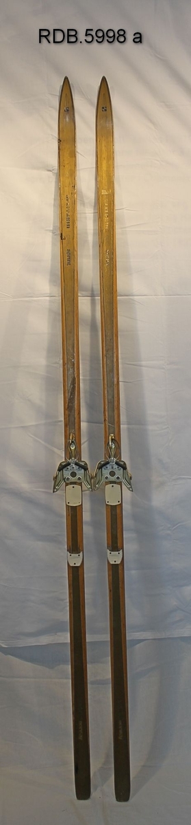 Et par laminerte treski. Trekvite med et bredt gullfarga felt kanta med en smal blå stripe langsetter skiet. Blå Splitkeinlogo på skituppen og blå påskrift. Påmontert gullfarga Rottefellabindinger. Bak disse er faststifta to kvite fotplater, den bakerste har metallkanter.