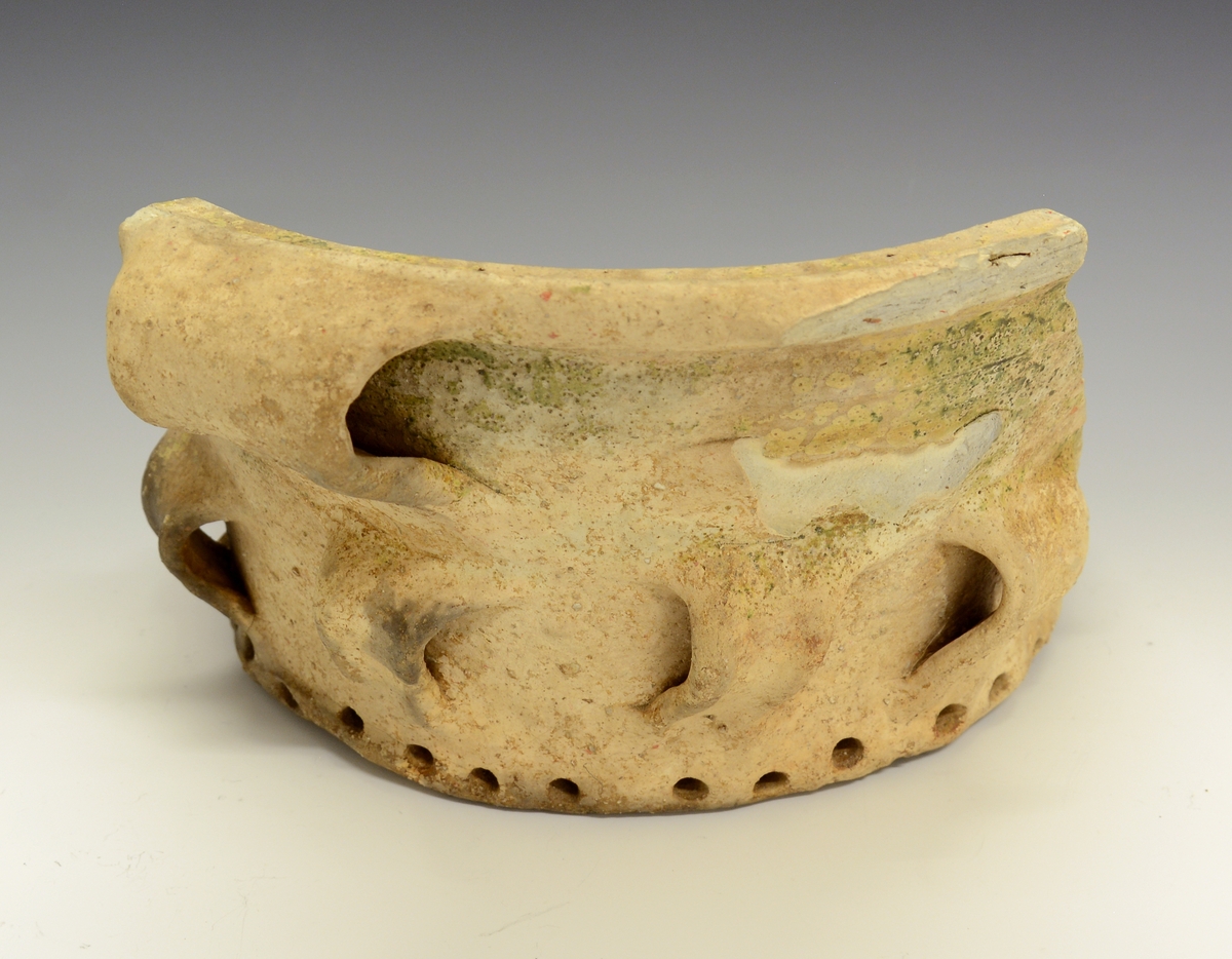 Fra protokollen: 
Keramikkskår. Tykt leirgods, flat bunn, utoverskrånende korpus som ender i en markert brutt kant oppe. Krukka har 4 dekorative ører nede på korpus og (1) og 2 større oppe. En mengde hull går inn i godset i bunnen og fra sidene av bunnen. Krukka mangler glasur, men har partivis (delvis) et slags grønnaktig belegg. Litt over halvparten av bunnen er bevart, men det meste av korpus er slått vekk. Krukka ble funnet i den under BM.1964:198, i merknadene, omtalte Bølebåten.