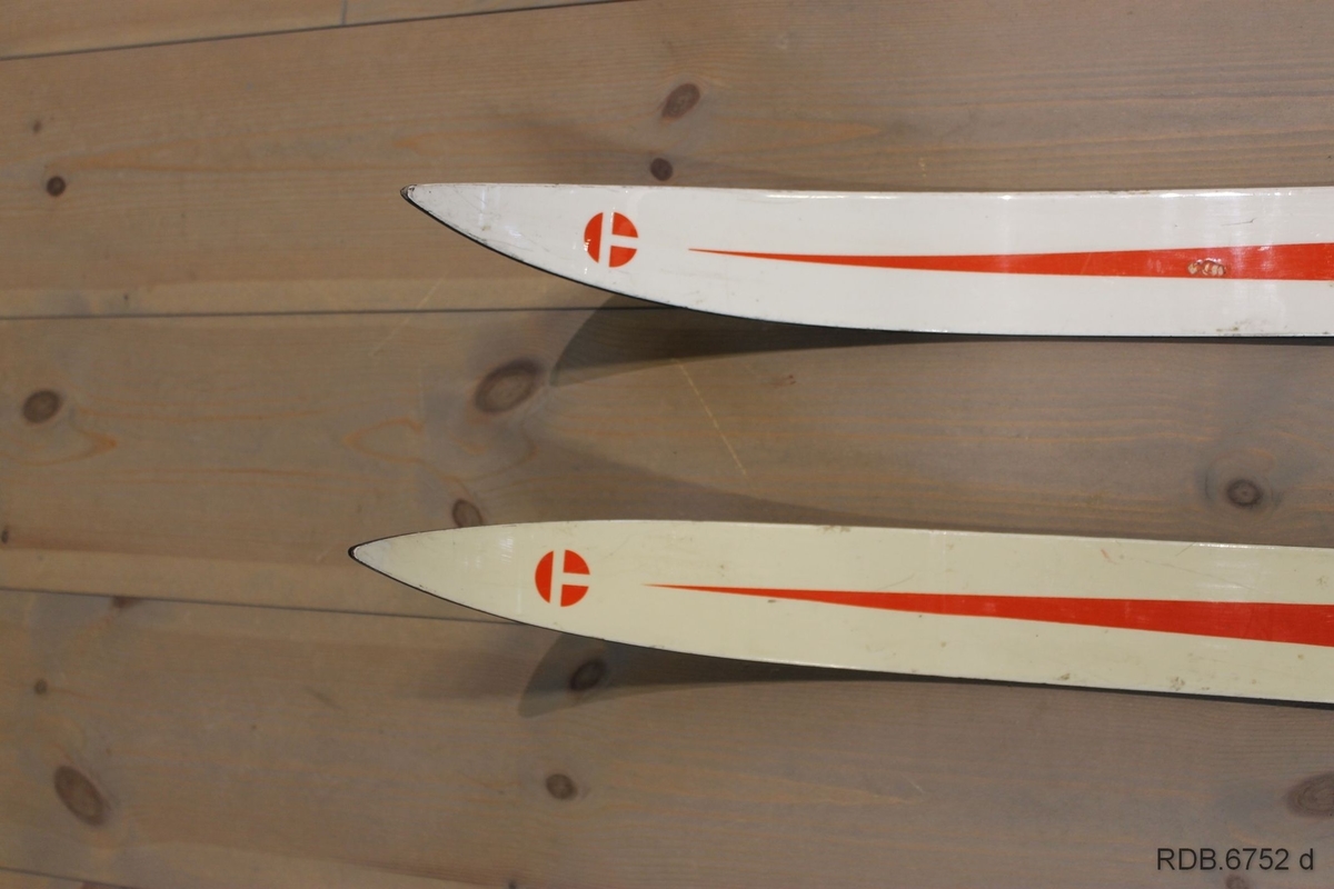 Et par Troll-ski, glassfiberski med trekjerne. Skiene er kvite med blå og røde dekorstriper og kvit påskrift. Skiene er jevnbrede men lett avfaset mot bakenden. Høg og spiss brett. Svarte sider og svart underside med ei egle. Påmontert blå Rottefellabindinger og kvit hælstøtte.