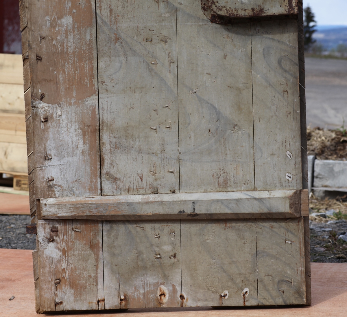 Døra er laget av 1 1/4 toms planker med to enkle drev som holder plankene sammen. Døra er belagt med profilert panel. Panelet er lagt på skrå i mønemønster og festet med spiker som har digre hoder. Døra har et vindu på 45 cm x 79 cm som innvendig er lukket med en liten hengslet dør. Døra er nærmest halvsirkelformet i toppen og passer da inn i buen i murverket. Låsen sitter på og har rombeformet nøkkelhullbeslag og to solide gangjern med to enkle knuter. Låsen sitter på innsida og er helt innebygd med jernplater og to slåtter. På innsida er rester etter påmalt marmorering.