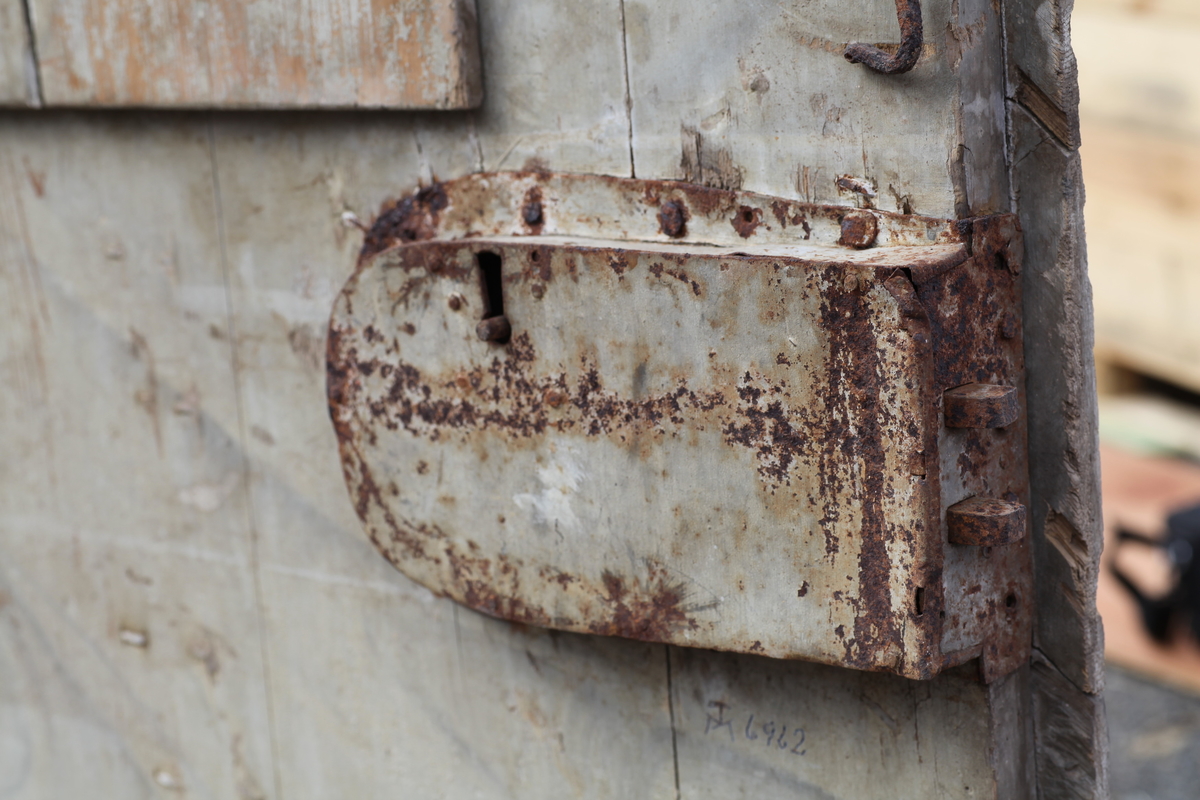 Døra er laget av 1 1/4 toms planker med to enkle drev som holder plankene sammen. Døra er belagt med profilert panel. Panelet er lagt på skrå i mønemønster og festet med spiker som har digre hoder. Døra har et vindu på 45 cm x 79 cm som innvendig er lukket med en liten hengslet dør. Døra er nærmest halvsirkelformet i toppen og passer da inn i buen i murverket. Låsen sitter på og har rombeformet nøkkelhullbeslag og to solide gangjern med to enkle knuter. Låsen sitter på innsida og er helt innebygd med jernplater og to slåtter. På innsida er rester etter påmalt marmorering.
