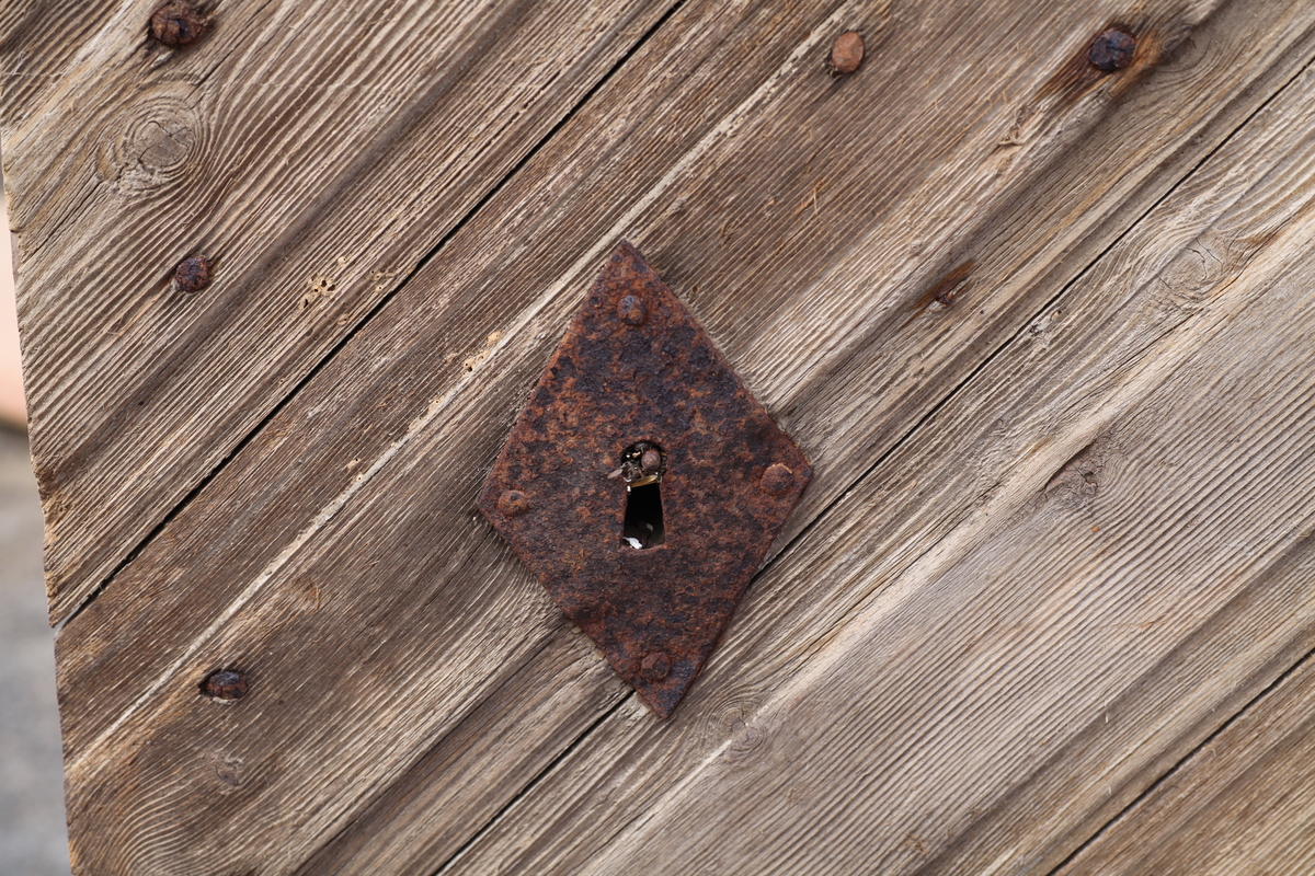 Døra er laget av 1 1/4 toms planker med to enkle drev som holder plankene sammen. Døra er belagt med profilert panel. Panelet er lagt på skrå i mønemønster og festet med spiker som har digre hoder. Døra har et vindu på 45 cm x 79 cm som innvendig er lukket med en liten hengslet dør. Døra er nærmest halvsirkelformet i toppen og passer da inn i buen i murverket. Låsen sitter på og har rombeformet nøkkelhullbeslag og to solide gangjern med to enkle knuter. Låsen sitter på innsida og er helt innebygd med jernplater og to slåtter. På innsida er rester etter påmalt marmorering.