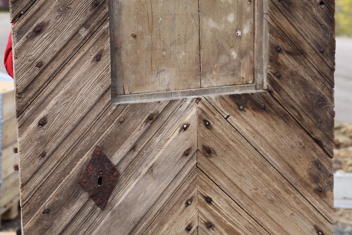 Døra er laget av 1 1/4 toms planker med to enkle drev som holder plankene sammen. Døra er belagt med profilert panel. Panelet er lagt på skrå i mønemønster og festet med spiker som har digre hoder. Døra har et vindu på 45 cm x 79 cm som innvendig er lukket med en liten hengslet dør. Døra er nærmest halvsirkelformet i toppen og passer da inn i buen i murverket. Låsen sitter på og har rombeformet nøkkelhullbeslag og to solide gangjern med to enkle knuter. Låsen sitter på innsida og er helt innebygd med jernplater og to slåtter. På innsida er rester etter påmalt marmorering.