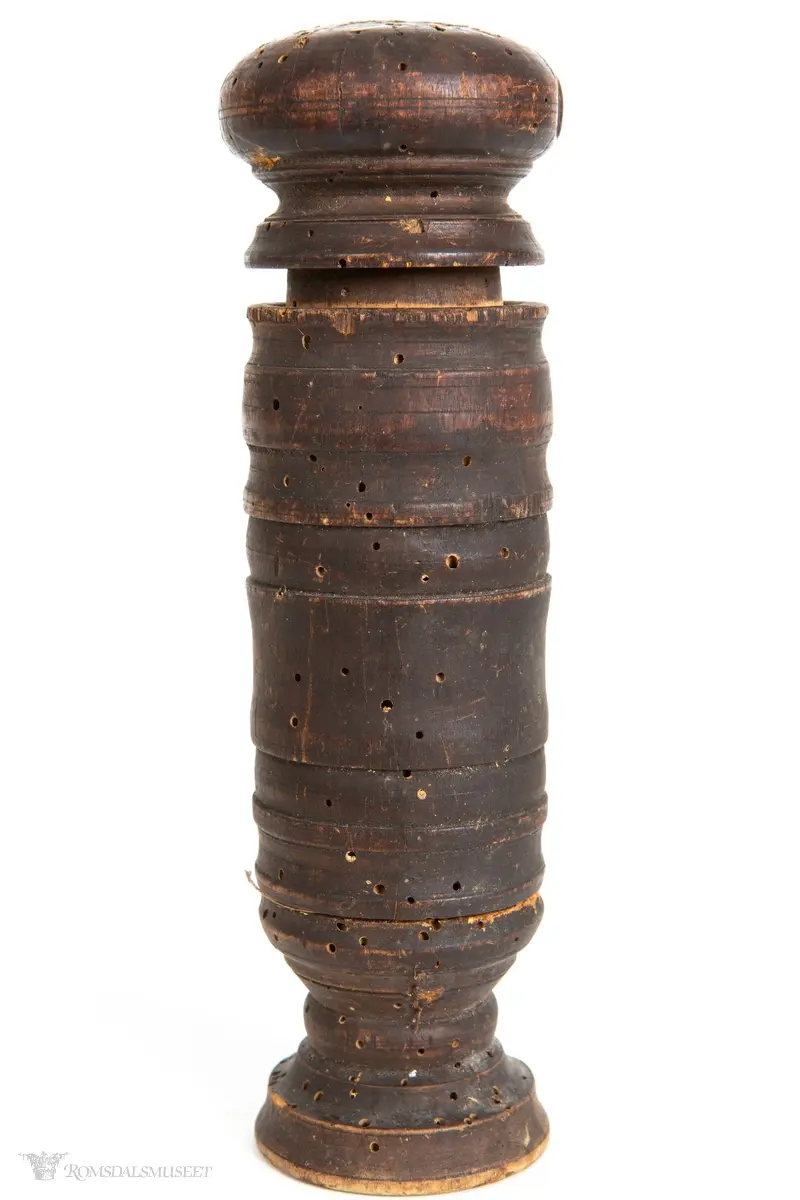 Dreid hylse med liten stett, og pistill med rundt, flatt håndgrep. Jernplate spikret fast i enden av pistillen.