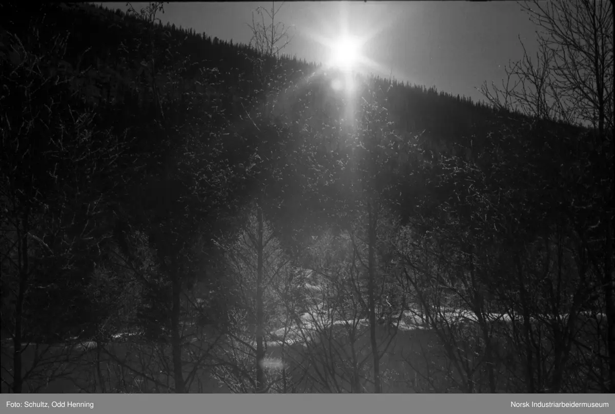 Solen sees over fjellet i snølandskapet.