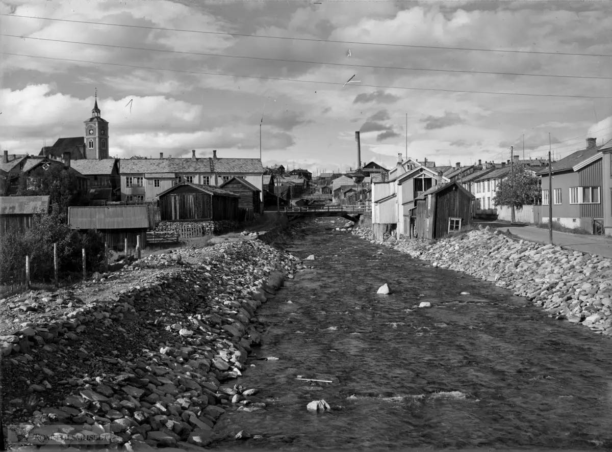 Røros. Fra Kvennhusbrua og oppover Hyttelva mot Smelthytta. T.h. avisa Fjell-Ljom som holdt tilholdt på elvekanten.