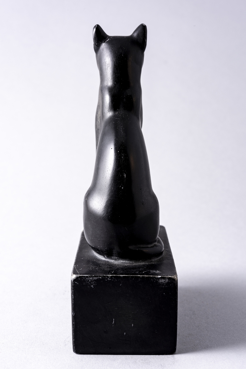 Figur i sortmalt keramikk av katt på firkantet base. Har tilhørt Sara Fabricius.
