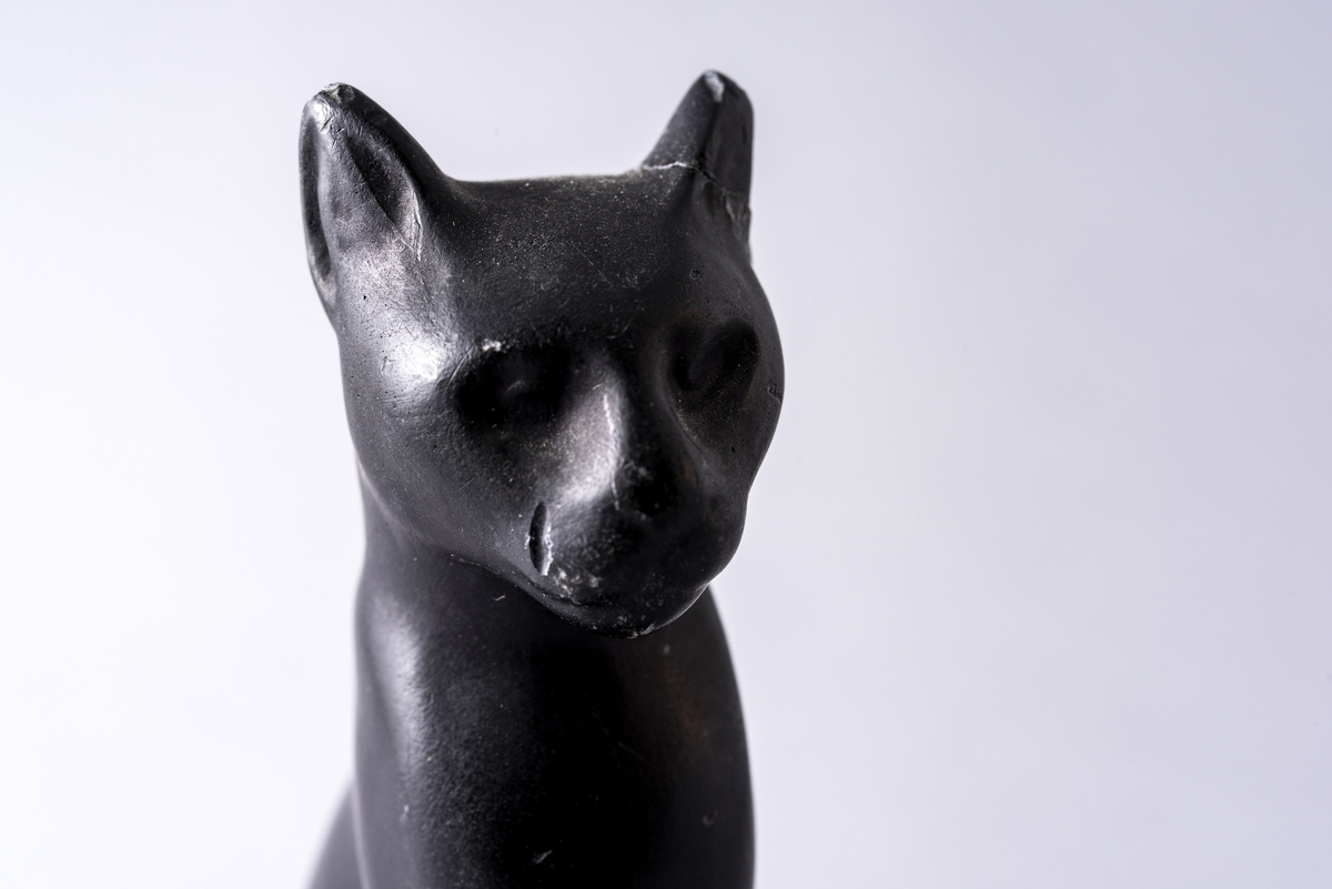 Figur i sortmalt keramikk av katt på firkantet base. Har tilhørt Sara Fabricius.