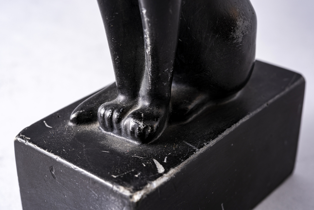 Figur i sortmalt keramikk av katt på firkantet base. Har tilhørt Sara Fabricius.