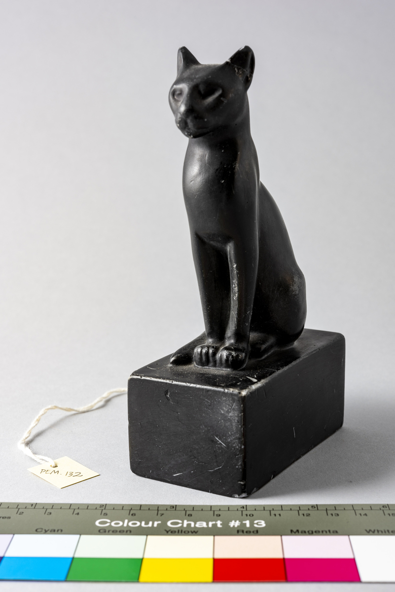 Figur i sortmalt keramikk av katt på firkantet base. Har tilhørt Sara Fabricius.