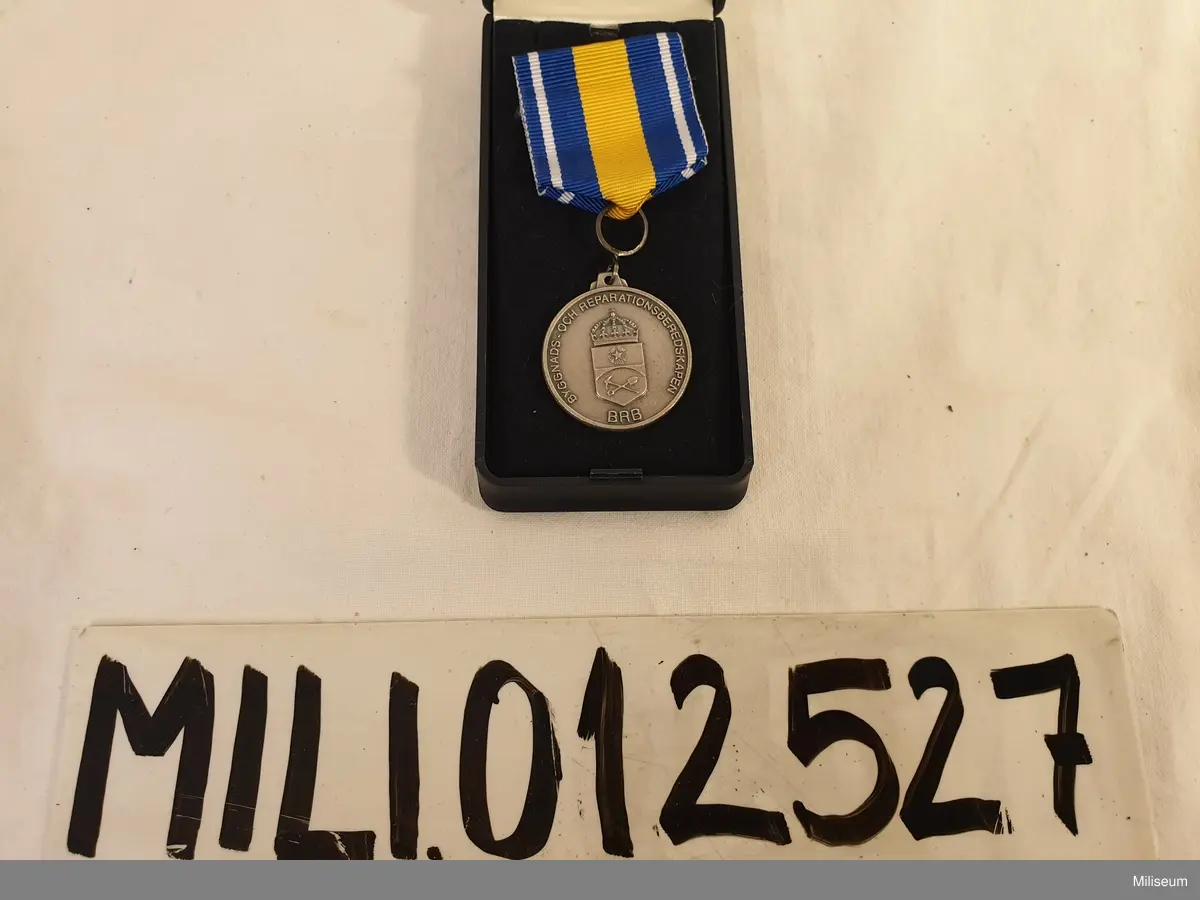 Hemvärnets förtjänstemedalj i valören silver, tillverkad av försilvrad mässing, med tillhörande miniatyrmedalj, extra ripsband och etui av blå plast.