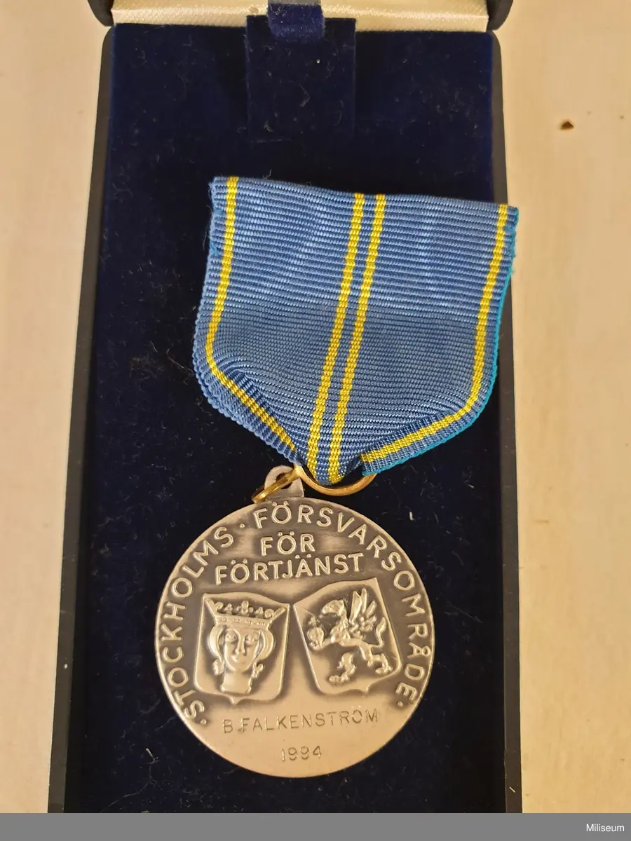 Hemvärnets förtjänstemedalj i valören silver, tillverkad av försilvrad mässing, med tillhörande etui av blå plast.