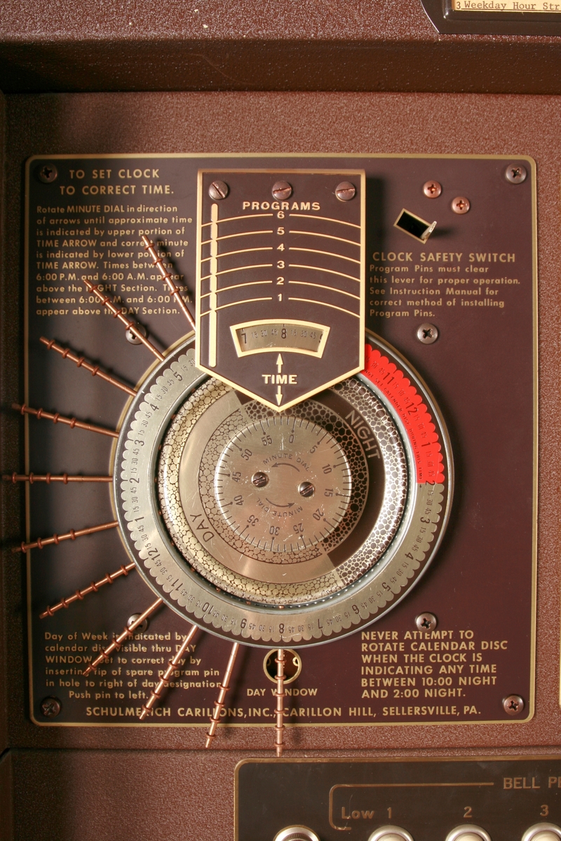 To brunmalte skap i metall (samme størrelse). Flere ventilasjonsrister.

Det ene skapet (A) inneholder avspiller, forsterker, klokkemekanikk, liten høytaler og øvrig elektronikk (noen deler ser ut å mangle). 
Øvre halvdel: bak pleksiglass som kan lukkes er styresentralen med instillinger for ulike klokkeprogrammer:
Til høyre er switch-knapper for å aktivere de tre funksjonene 
a) avspilling av musikkrull 
b) bruk av manuelt spillebord og 
c) timeslag.

Over til venstre er en timer for å skjemalegge de ulike aktivitetene:
1) Hverdag avspilling musikkrull
2) Søndag avspilling musikkrull
3) Hverdag avspilling timeslag
4) Søndag avspilling timeslag
5) Hverdag avspilling manuelt spillebord
6) Søndag avspilling manuelt spillebord

I tillegg er et eget panel for å velge ulike fomer av klokkeringinger ('BELL PEAL').

Nedre halvdel: Musikkrullmekanikk med en mekanisk avleser for musikkrullene ('tracker bar'). 30 spor; én for én tone hver. Papirullen løper over en rekke fjærbelastede(?) L-formet tangenter, en for hvert spor. Når et hull passerer en tangent løftes tangenten oppover og gir i sin tur et signal videre om å aktivere akkurat denne tonen.

Det andre skapet (B) idag tomt, usikker funksjon. Har strømforsyning. Sannsynlig forsterker for bruk av høytalere (C-F) i klokketårnet. Se elektronikk (H). Muligens også oppbevaring av musikkruller med mer.