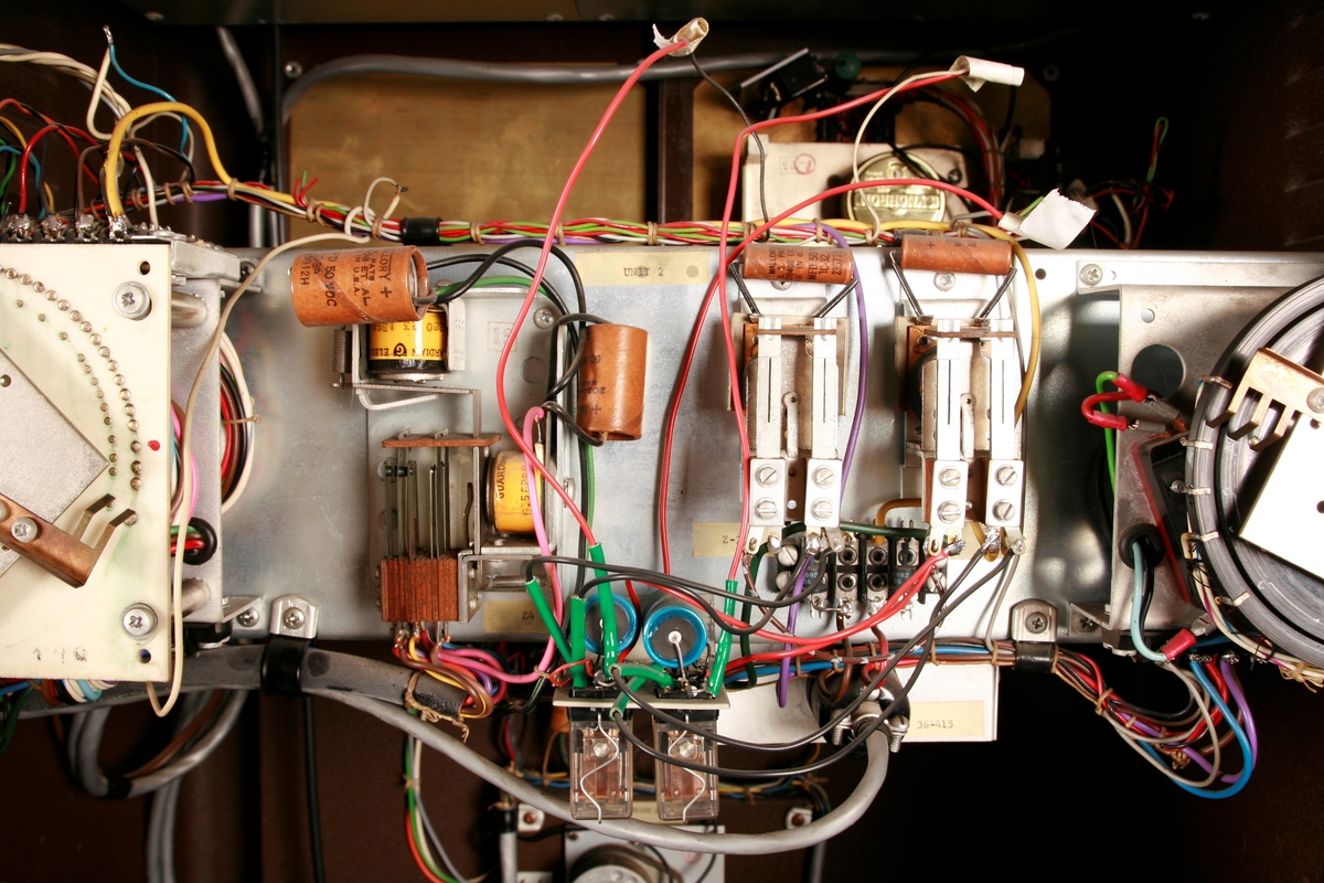 To brunmalte skap i metall (samme størrelse). Flere ventilasjonsrister.

Det ene skapet (A) inneholder avspiller, forsterker, klokkemekanikk, liten høytaler og øvrig elektronikk (noen deler ser ut å mangle). 
Øvre halvdel: bak pleksiglass som kan lukkes er styresentralen med instillinger for ulike klokkeprogrammer:
Til høyre er switch-knapper for å aktivere de tre funksjonene 
a) avspilling av musikkrull 
b) bruk av manuelt spillebord og 
c) timeslag.

Over til venstre er en timer for å skjemalegge de ulike aktivitetene:
1) Hverdag avspilling musikkrull
2) Søndag avspilling musikkrull
3) Hverdag avspilling timeslag
4) Søndag avspilling timeslag
5) Hverdag avspilling manuelt spillebord
6) Søndag avspilling manuelt spillebord

I tillegg er et eget panel for å velge ulike fomer av klokkeringinger ('BELL PEAL').

Nedre halvdel: Musikkrullmekanikk med en mekanisk avleser for musikkrullene ('tracker bar'). 30 spor; én for én tone hver. Papirullen løper over en rekke fjærbelastede(?) L-formet tangenter, en for hvert spor. Når et hull passerer en tangent løftes tangenten oppover og gir i sin tur et signal videre om å aktivere akkurat denne tonen.

Det andre skapet (B) idag tomt, usikker funksjon. Har strømforsyning. Sannsynlig forsterker for bruk av høytalere (C-F) i klokketårnet. Se elektronikk (H). Muligens også oppbevaring av musikkruller med mer.