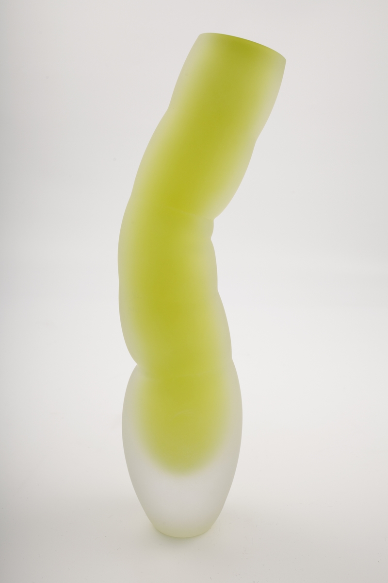 Vase i underfangsglass. Et sjikt i opakt grønnfarget glass innerst, deretter et tykt sjikt i klart glass. Flerleddet kuleformet korpus, hvis ytterside er mattet ved hjelp av sandblåsing. Vasens sirkulære munning er planslipt.