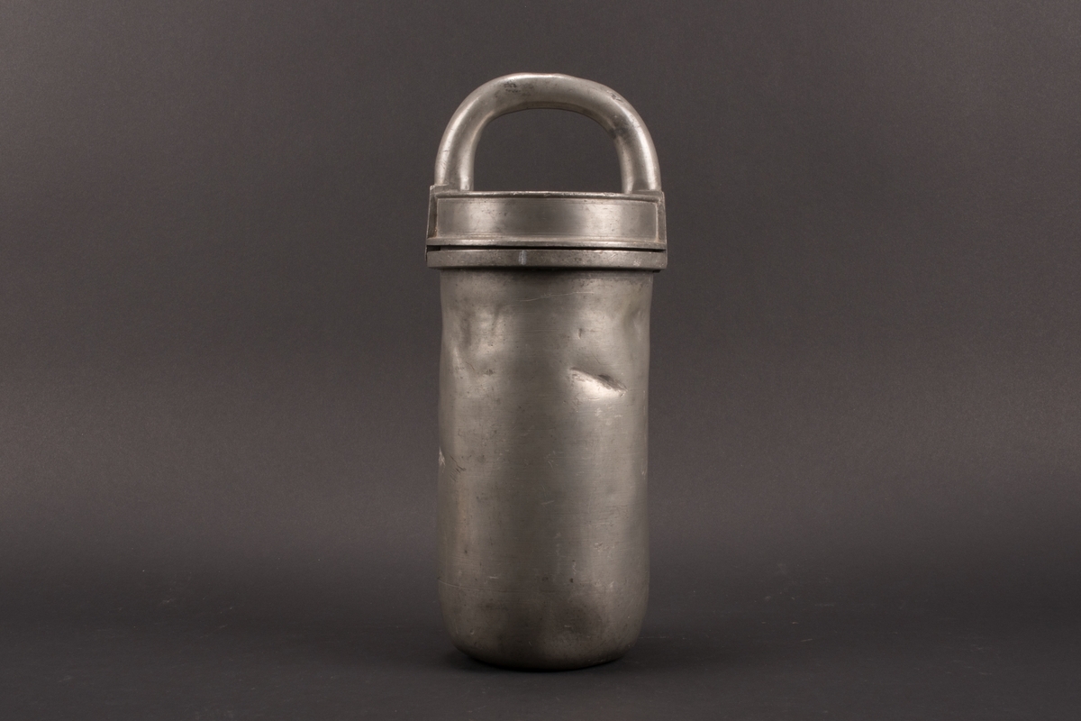 Cylindrisk glassform av tenn. Lock med halvcirkelformat handtag. Formens botten är något rundad.