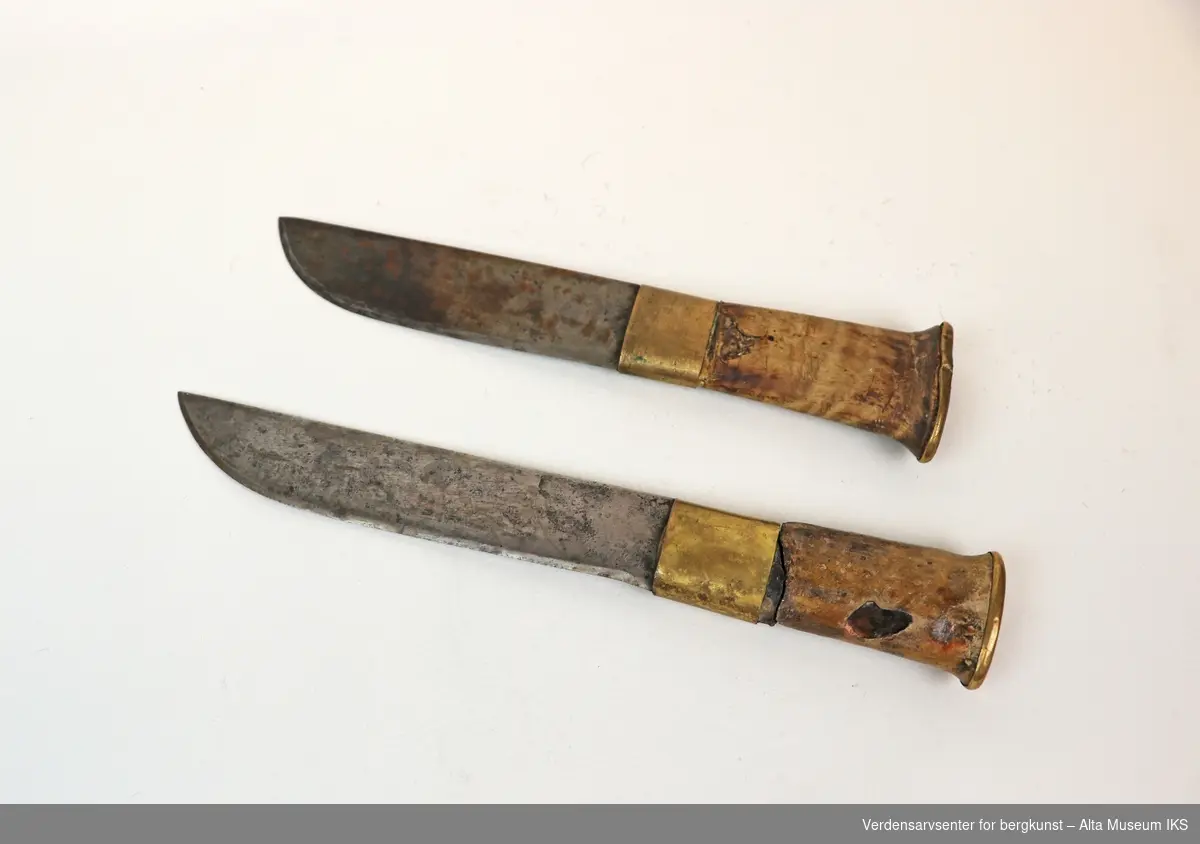 To kniver i forskjellige størrelser, med blad i jern og skaft av tre. Knivfeste og avslutning på skaft er belagt med messing.