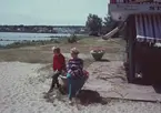 På bilden syns två kvinnor sittande vid en kiosk på en badstrand.