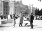 Prins Carl och prinsessan Louise samt svenskbybornas ledare skolläraren Kristoffer Hoas framför kasernbyggnaden på Ryhov i Jönköping.