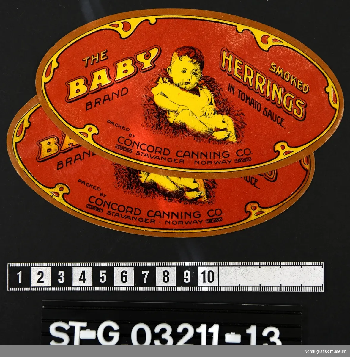 To ovale etiketter i rød, brun og gul, med en baby som hovedmotiv. 

"Smoked herrings in tomato sauce"