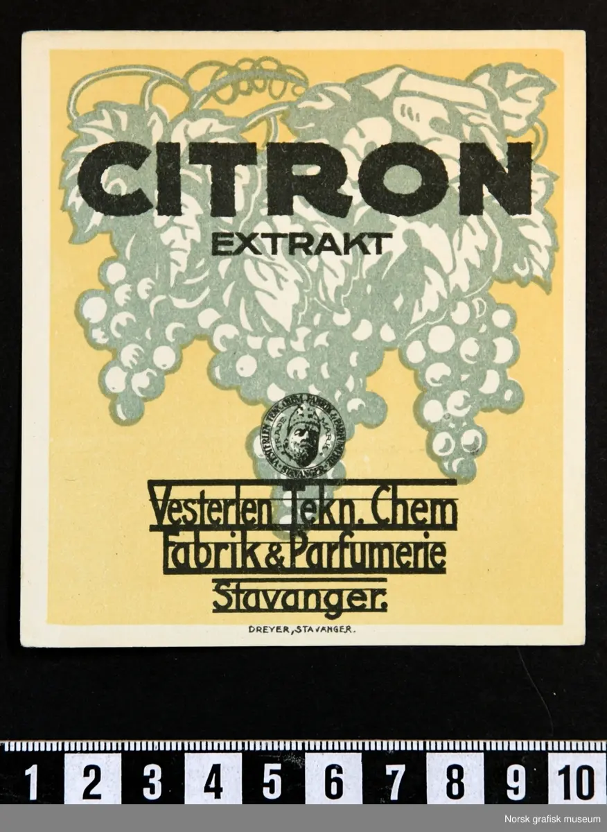 Firkantet etikett med stiliserte druer i grønt, på lys gul bakgrunn. Over er teksten i sort: 
"Citron extrakt"