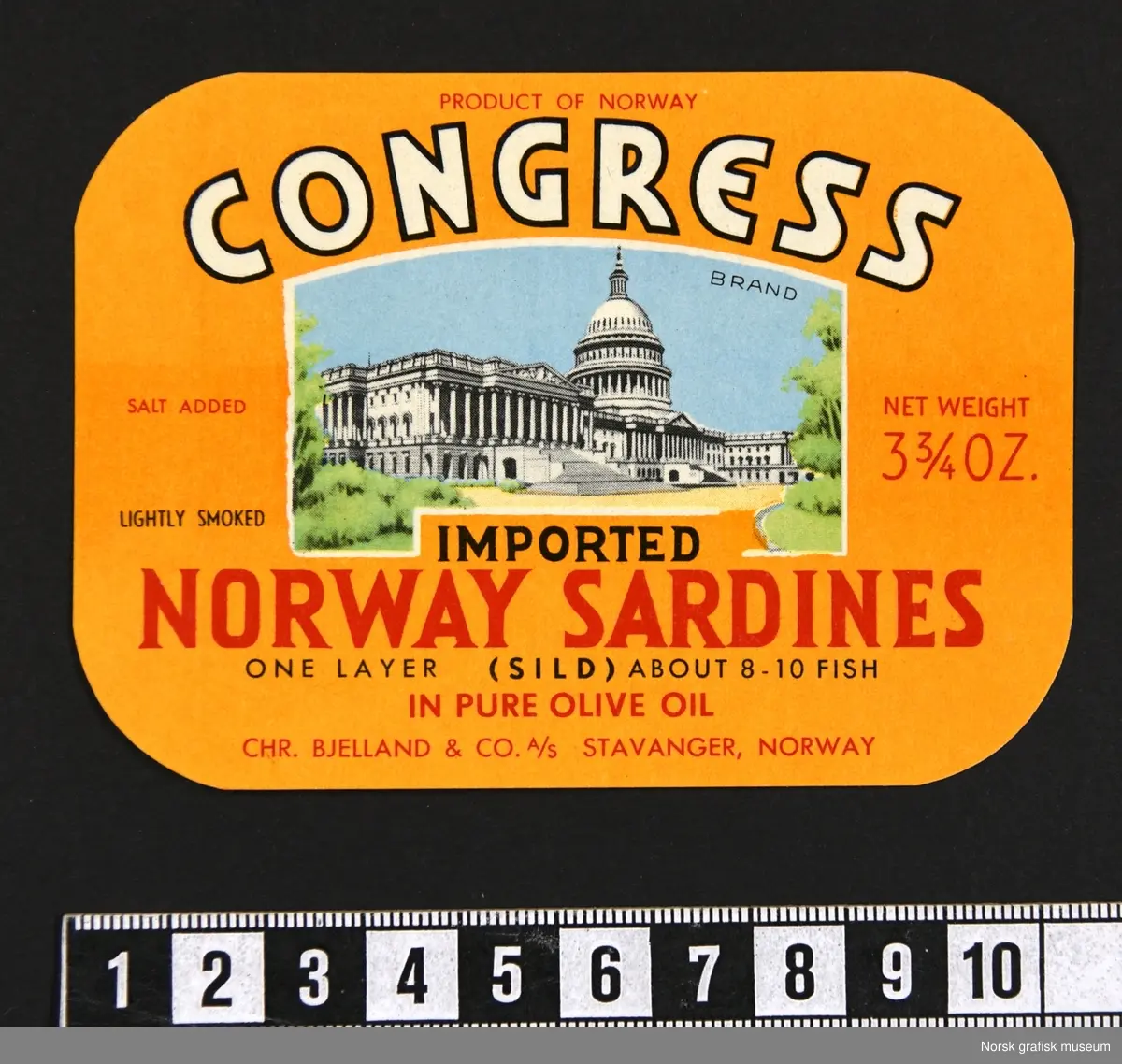 Etikett med oransje bakgrunnsfarge. Midt på etiketten er en fremstilling av United States Capitol, også kjent som Capitol building, Capitol bygningen, i Washington D.C.

"Imported Norway sardines in pure olive oil"