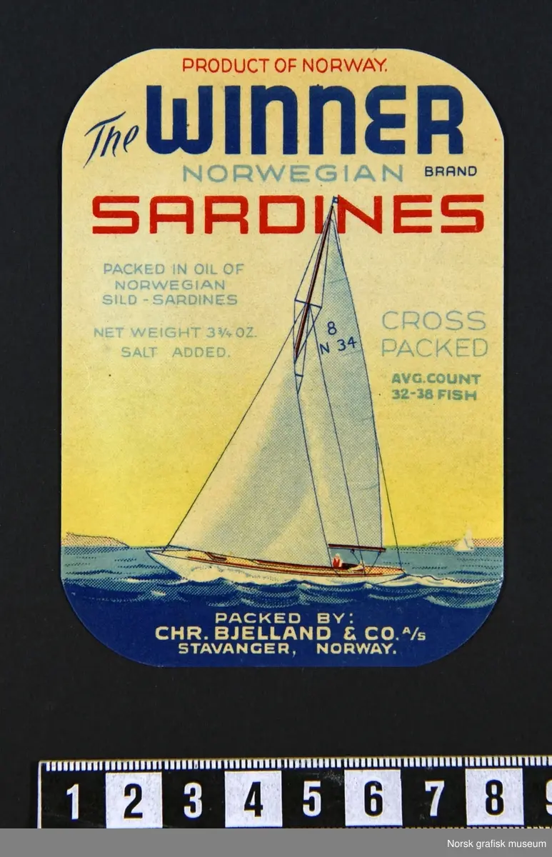 Etiketter med fremstilling av en seilbåt med hvite seil, på blått hav, under en gul himmel. 

"Sardines packed in oil of Norwegian sild- sardines"