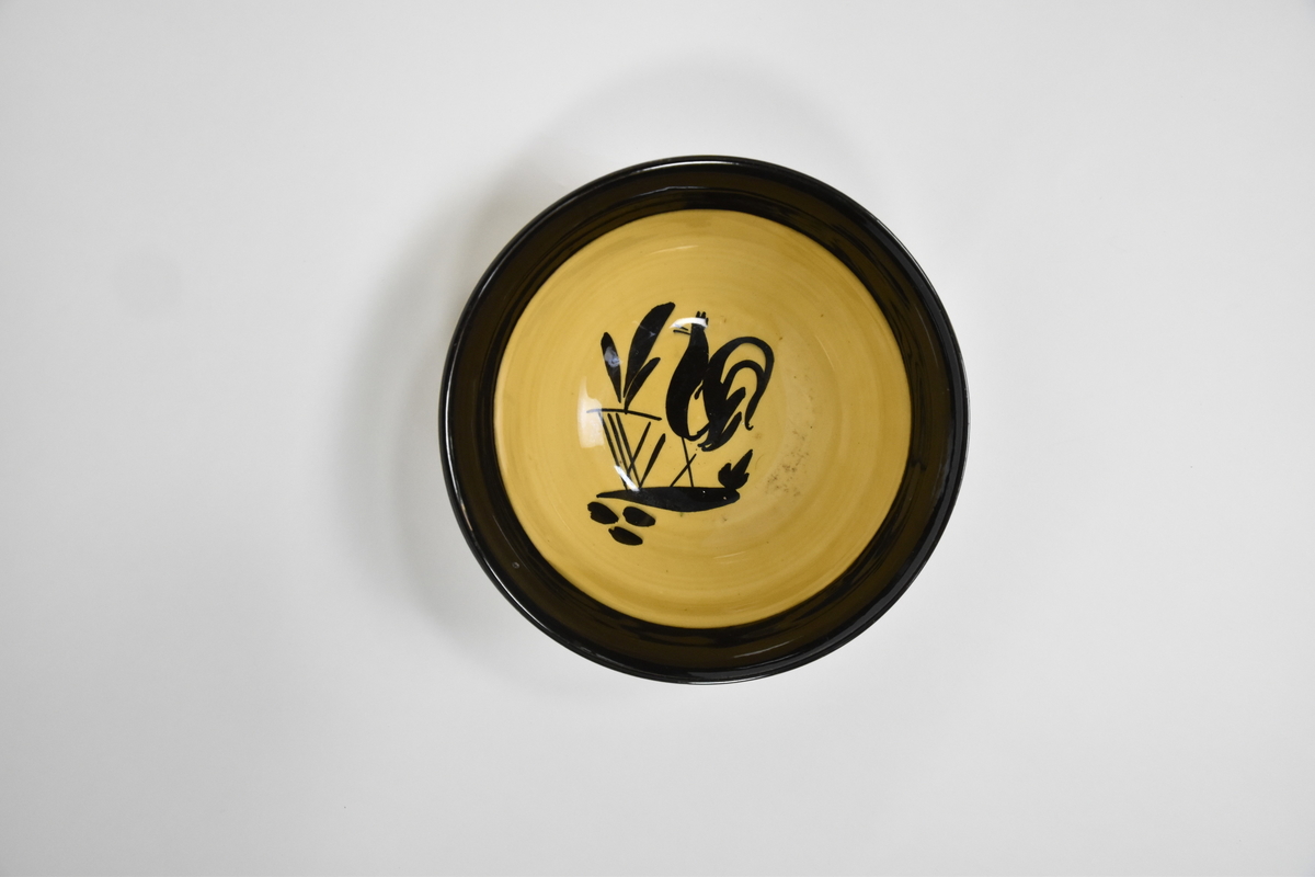 Bolle til mokkaservise, gult med svart pynt, bestående av 30 deler. Serviset er brukt som dokkestell. Dokkestell ble gitt til jenter til lek som forberedelse til voksenlivet. 