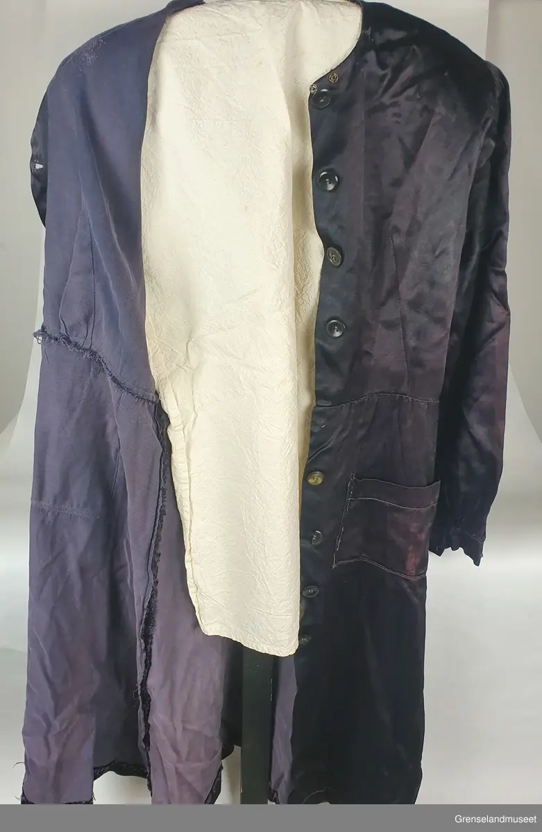 Sprt forkelkjole. Sydd av kåpefor. Bølankt stoff, muligens viskose (kunstsilke). Maskinsydde sømmer, Sårkanter overkastet med hånd. Håndsydde knapphul. Knappene fra kåpa.