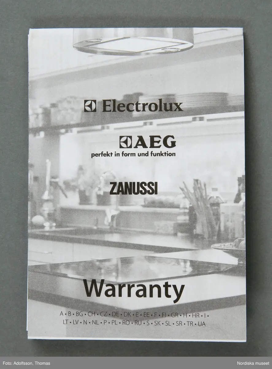 En elektrisk råsaftcentrifug av märket Elektrolux PERFECTJUICE ESF 2000. Består av  6 delar. a) Själva råsaftcentrifugen är cylinderformad och av metall och plast. De övriga delarna är av rökgrå hårdplast och består av b+) ett lock med c) press samt en d) behålllare som fruktköttet samlas i och e) en liten lockförsedd juicekanna med f) skumseparator i form av en plasskena som saften rinner ut i när den är klar. Dessutom en g) bruksanvisningsbroschyr och ett h) garantipapper.
Locket (b+) har en skada där en bit är avslagen.

Lena Kättström Höök 2014-01-10