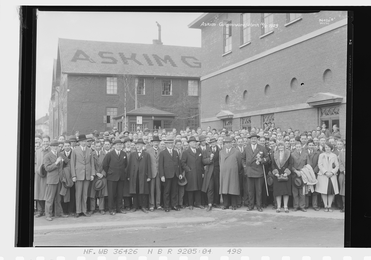 Gruppe mennesker fra bla. Handelsgymnasiet foran fabrikkbygning, Askim gummivarefabrikk A/S. "Askim Gummivarefabrikk 156/5-1929".