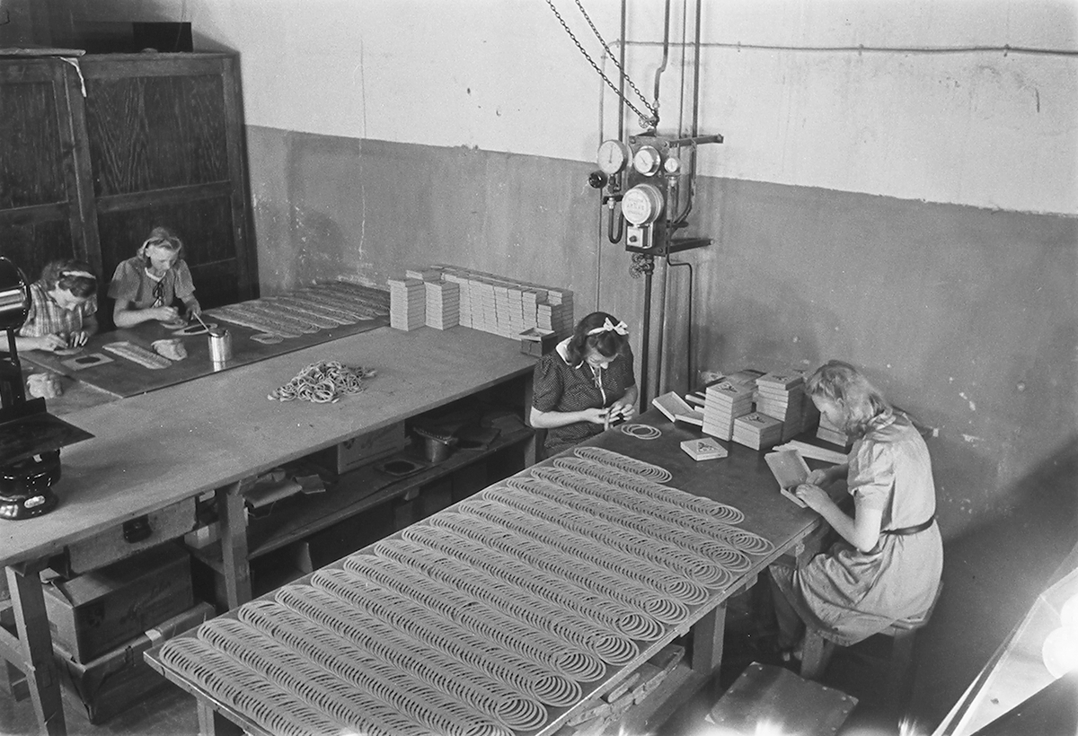 Ansatte i produksjonshallen. Den Norske Kalosje- & Gummivarefabrikk A/S, senere Mjøndalen Gummivarefabrikk, Eiker. Fotografert 1940.