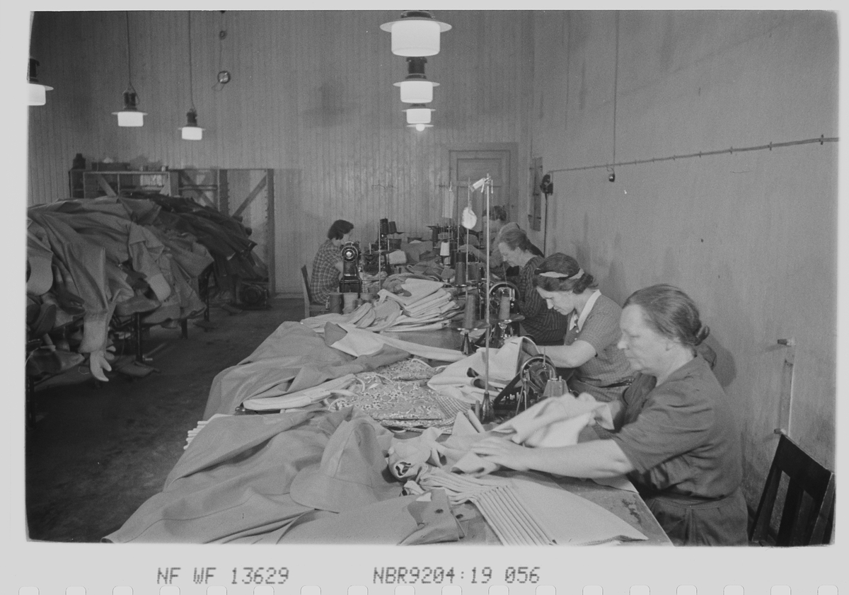 Kvinnelige ansatte i produksjon av gummitøy. Den Norske Kalosje- & Gummivarefabrikk A/S, senere Mjøndalen Gummivarefabrikk, Eiker. Fotografert 1940.