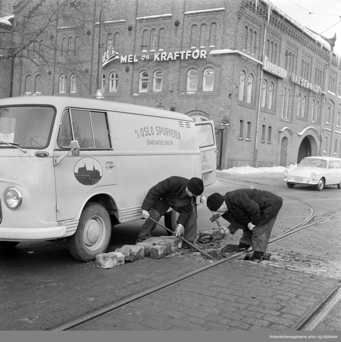 Sporveisarbeiderne Reidar Thomassen (til venstre) og Sverre Holte fra Oslo Sporveiers baneavdeling reparerer en av linjeskjøtene utenfor Bjølsen Valsemølle på Sandaker. Januar 1966.