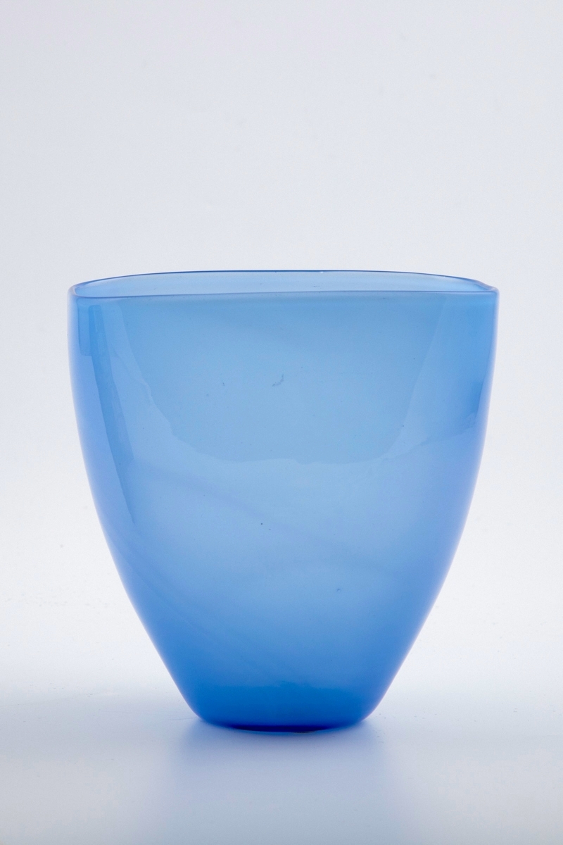 Konisk vase utført i lyseblå opaliserende glassmasse. Korpus hviler på en sirkulær fot, mens munningsranden er rektangulær. Noe hevet bunn med rester av puntemerke.